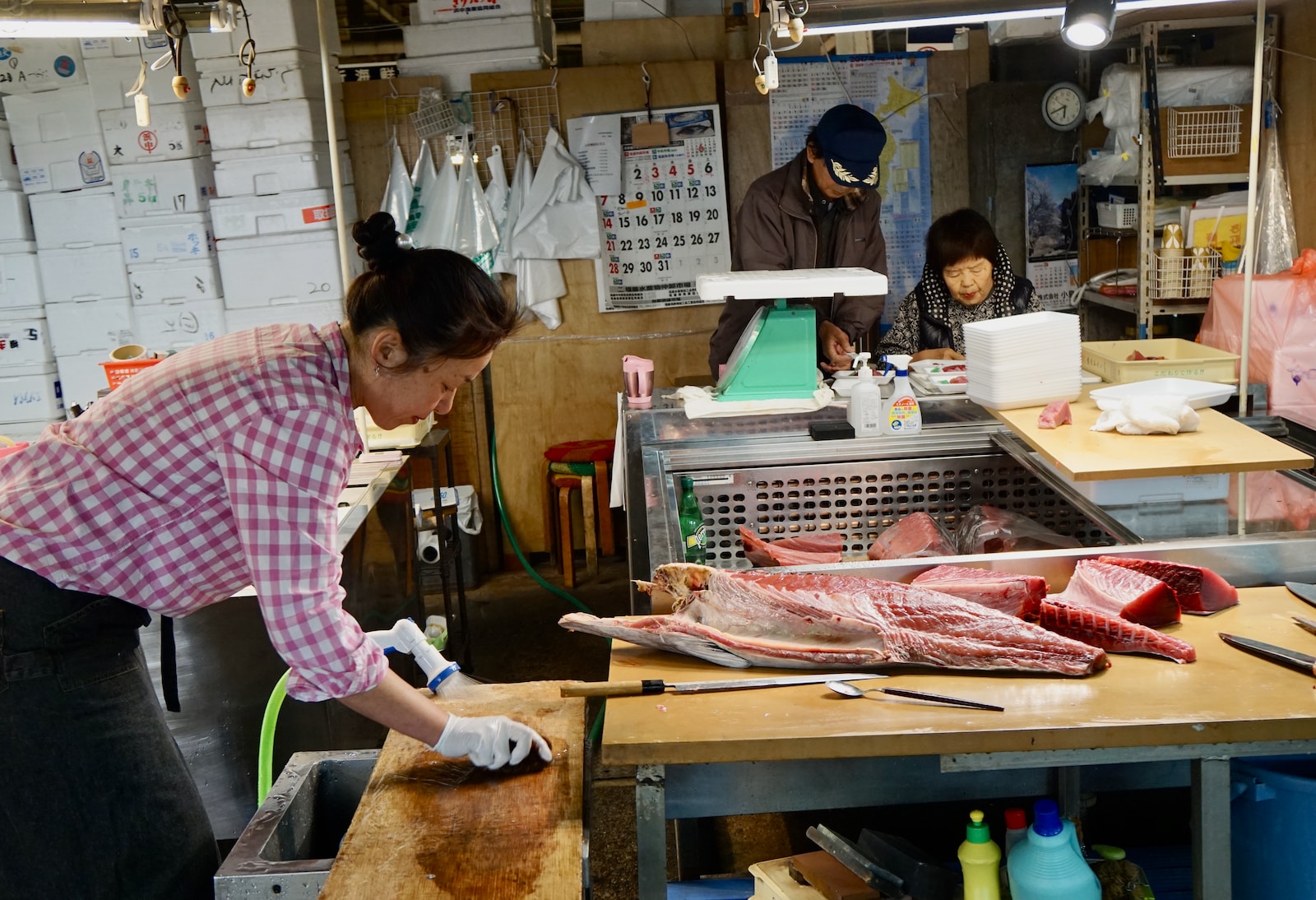 woman in pink and white long sleeve shirt slicing fish